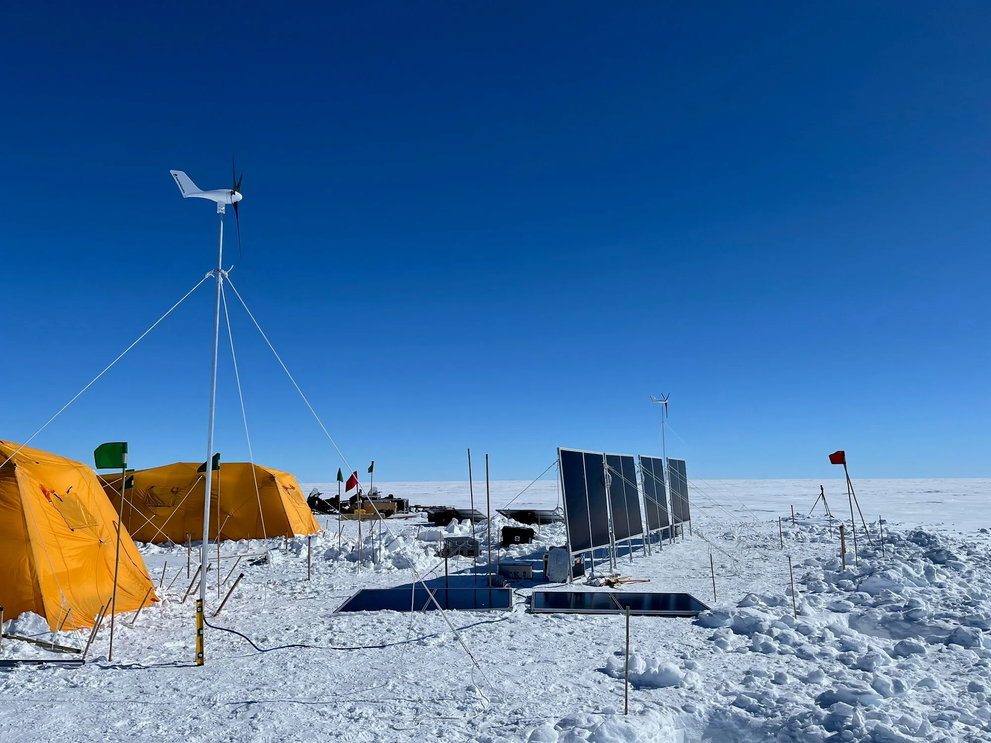 Wind turbine and vertical solar panels anchored to holes in the ice sheet