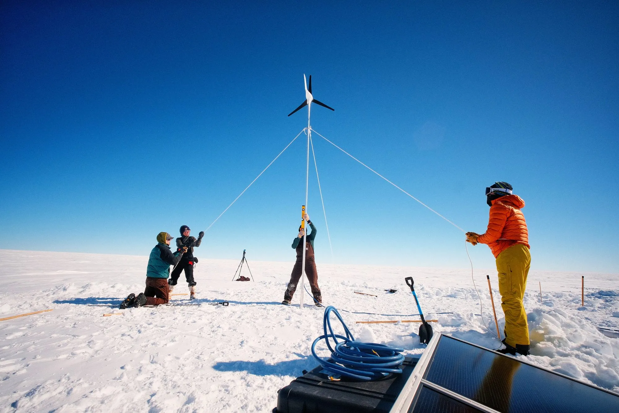 Four members of the install team hold and secure a wind turbine.